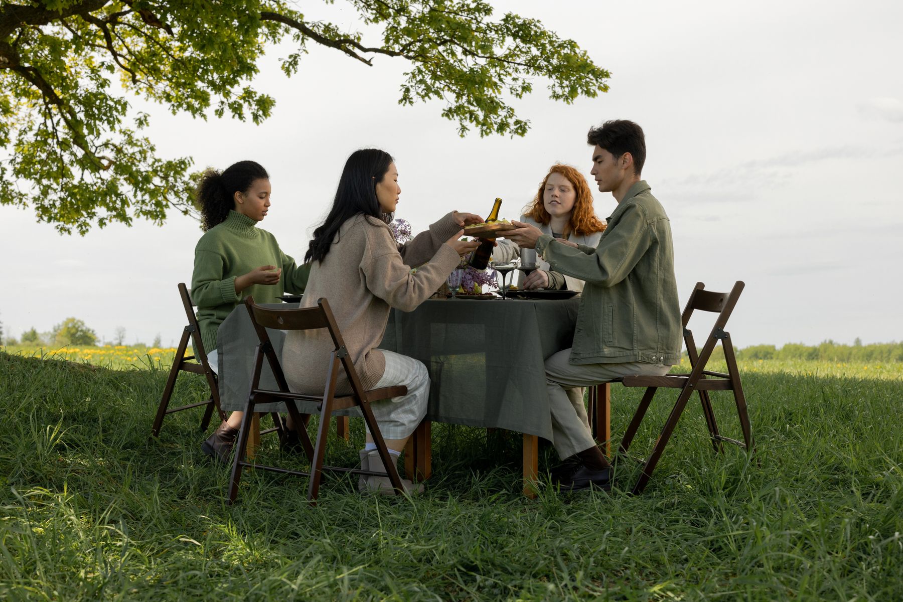 A group of people talking around a shared table outdoors.